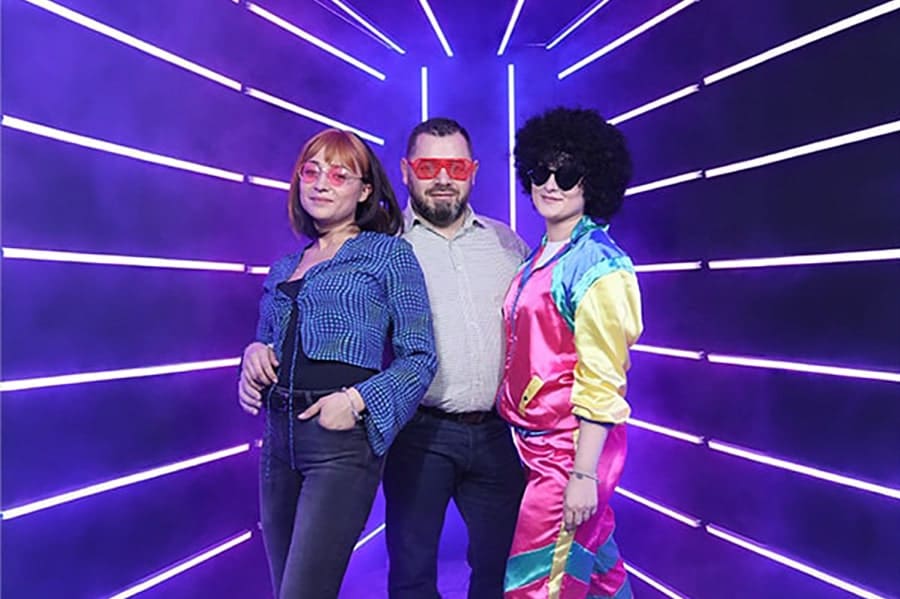 Trei participanti fotografiati la eveniment OMG Events intr-un decor modern cu lumini LED mov si accesorii retro, ideal pentru petreceri corporate, activari de brand, nunti si botezuri